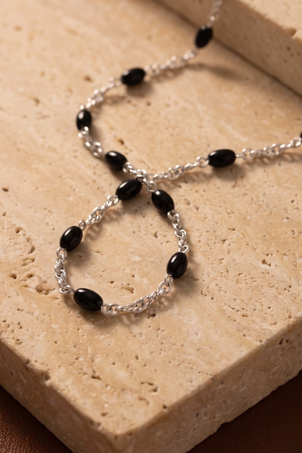 Dusk Chain aus 925 Sterlingsilber mit Onyx-Perlen auf Travertin